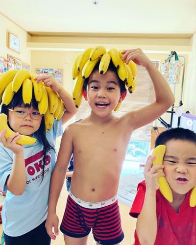 バナナを頭に乗せる幼い男の子2人と女の子1人